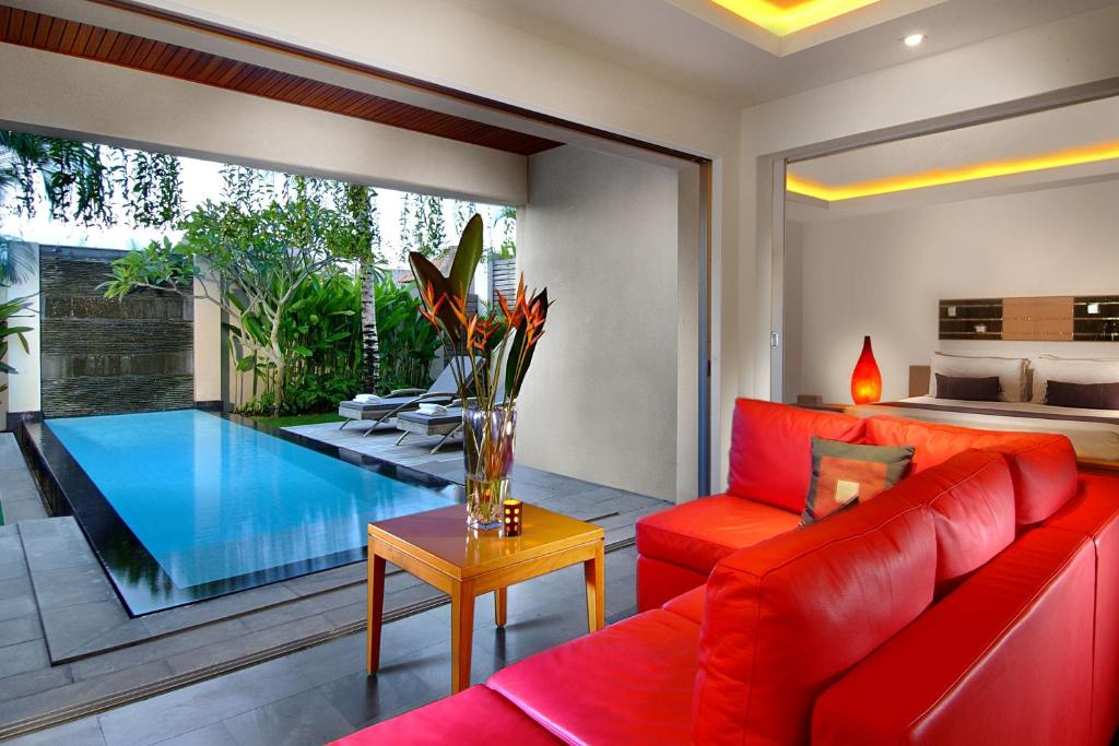 a living room with a red couch and a swimming pool at Bali Island Villas and Spa Seminyak in Seminyak