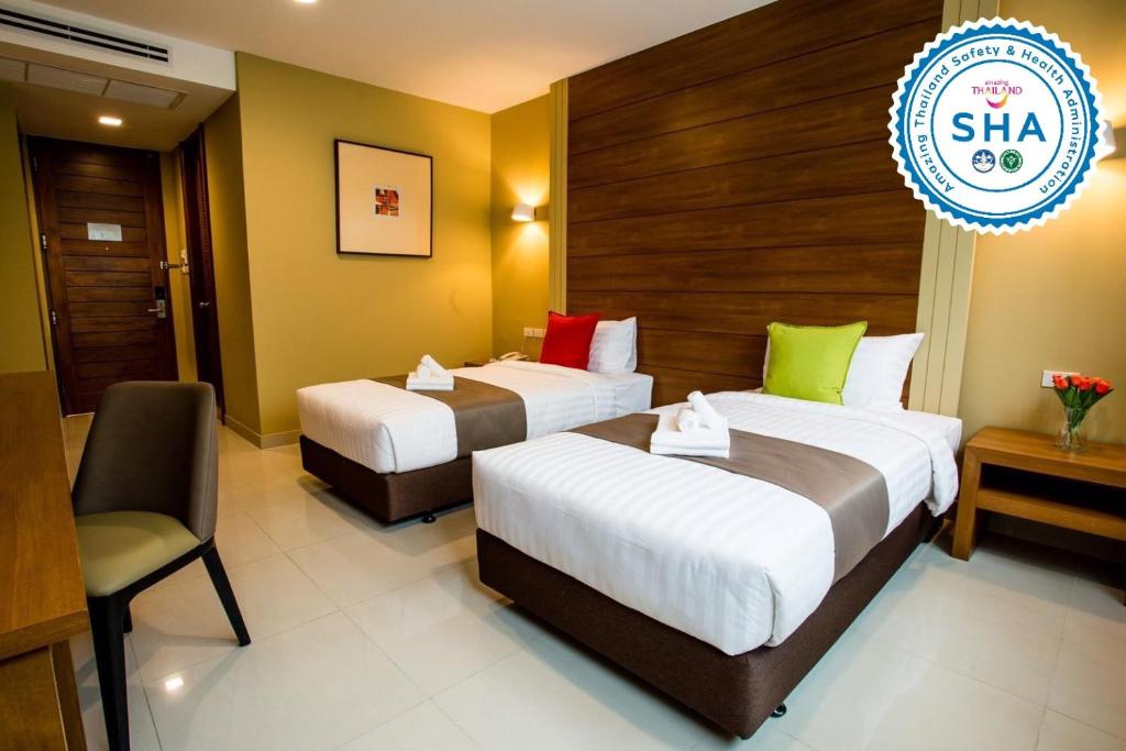 A twin room with two separate beds, a lounge chair and a wood accent wall.