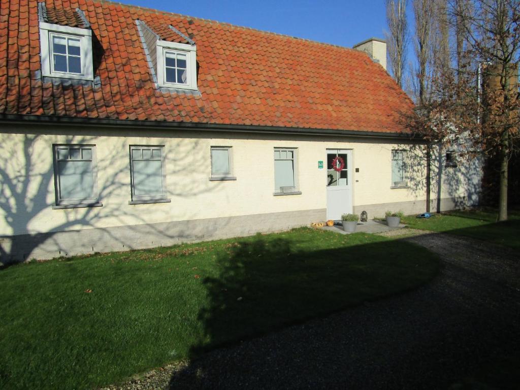 ein weißes Haus mit einem orangenen Dach und einem Hof in der Unterkunft B&B De Pethaan in Wielsbeke