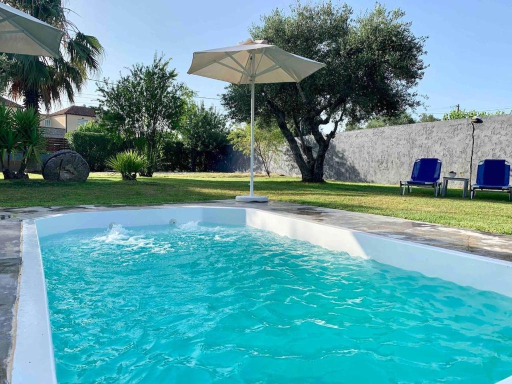 uma piscina com um guarda-sol e algumas cadeiras em Felenia House - Summer Escape em Vryses