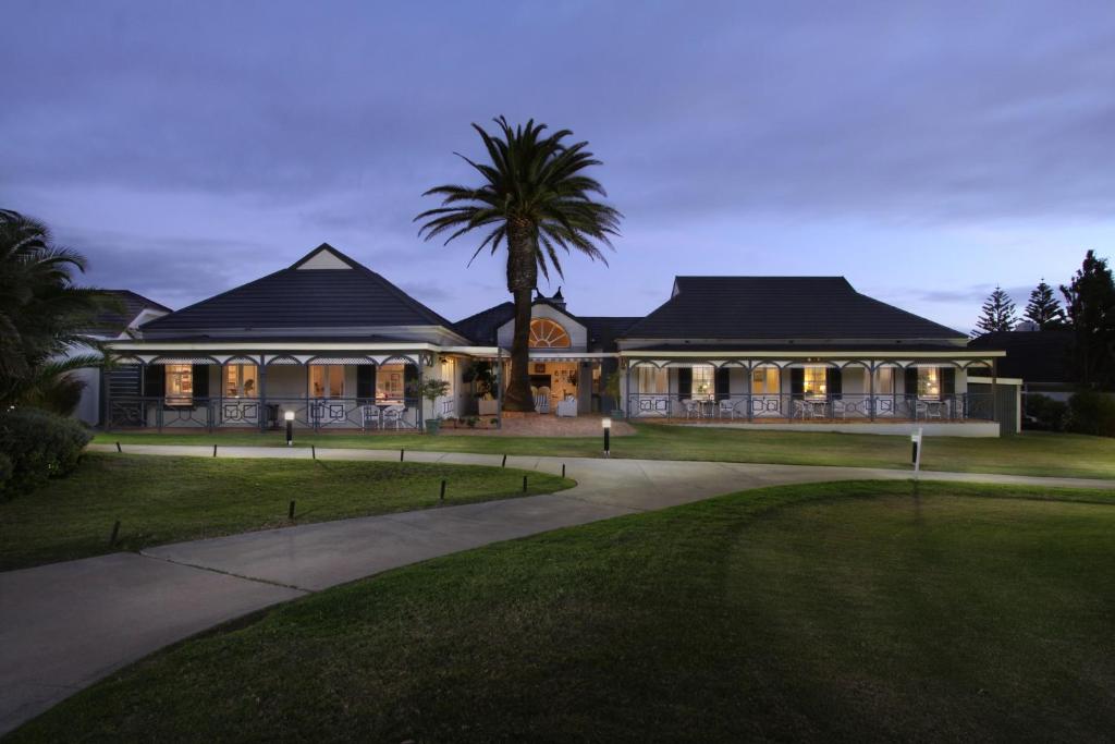 een huis met een palmboom ervoor bij 19th Hole Guest Lodge - Golfers paradise in Hermanus