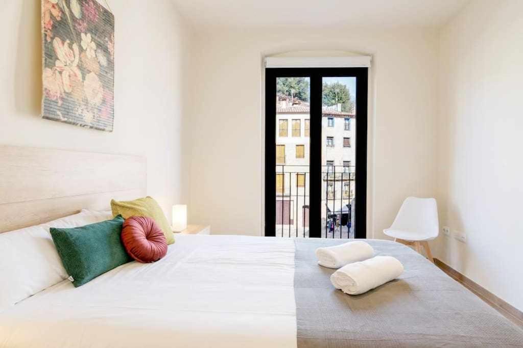 a bedroom with a large white bed with colorful pillows at Besalu 21 New stylish apt on Plaça Llibertat in Besalú