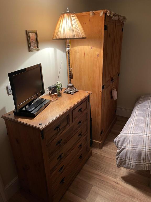 a bedroom with a wooden dresser with a computer on it at Deer Lodge in Thornton Curtis