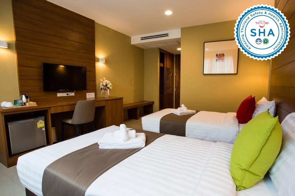 A styled twin room with two beds, television, work surface and compact refrigerator.