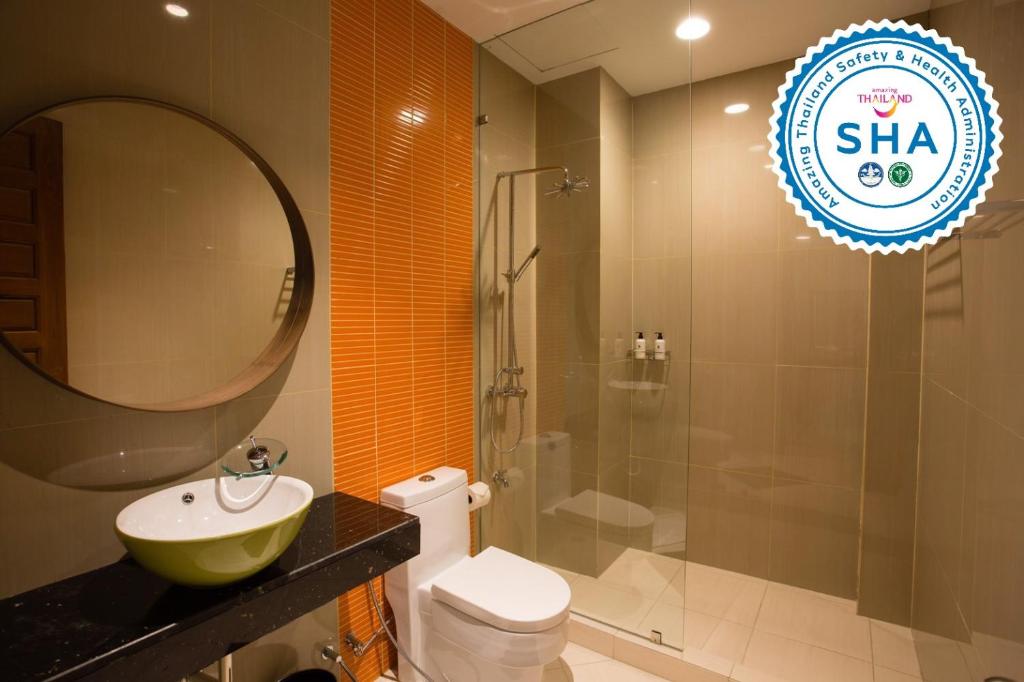 A modern tiled bathroom has a vessel sink, wall-hung toilet and glass-enclosed shower.