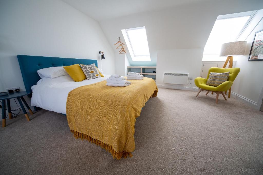 a bedroom with a bed with a yellow blanket and a chair at The Coffee Loft in Padstow