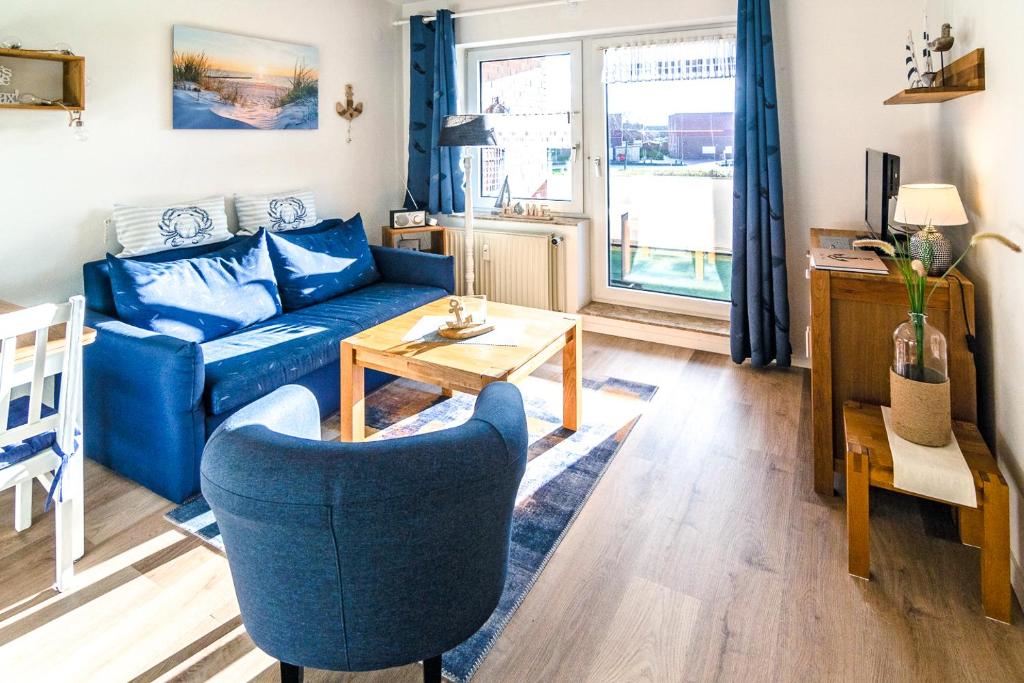 uma sala de estar com um sofá azul e uma mesa em Lüttje Nest em Dornumersiel