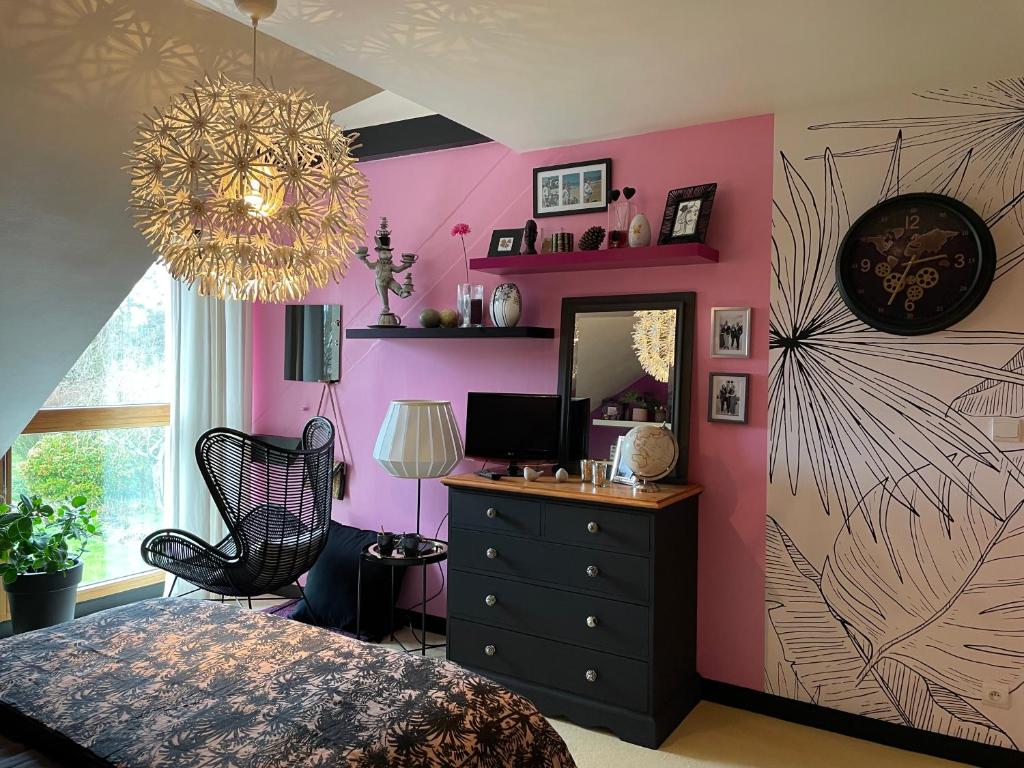 a bedroom with a pink wall with a dresser and a mirror at Chez Béa in Granville