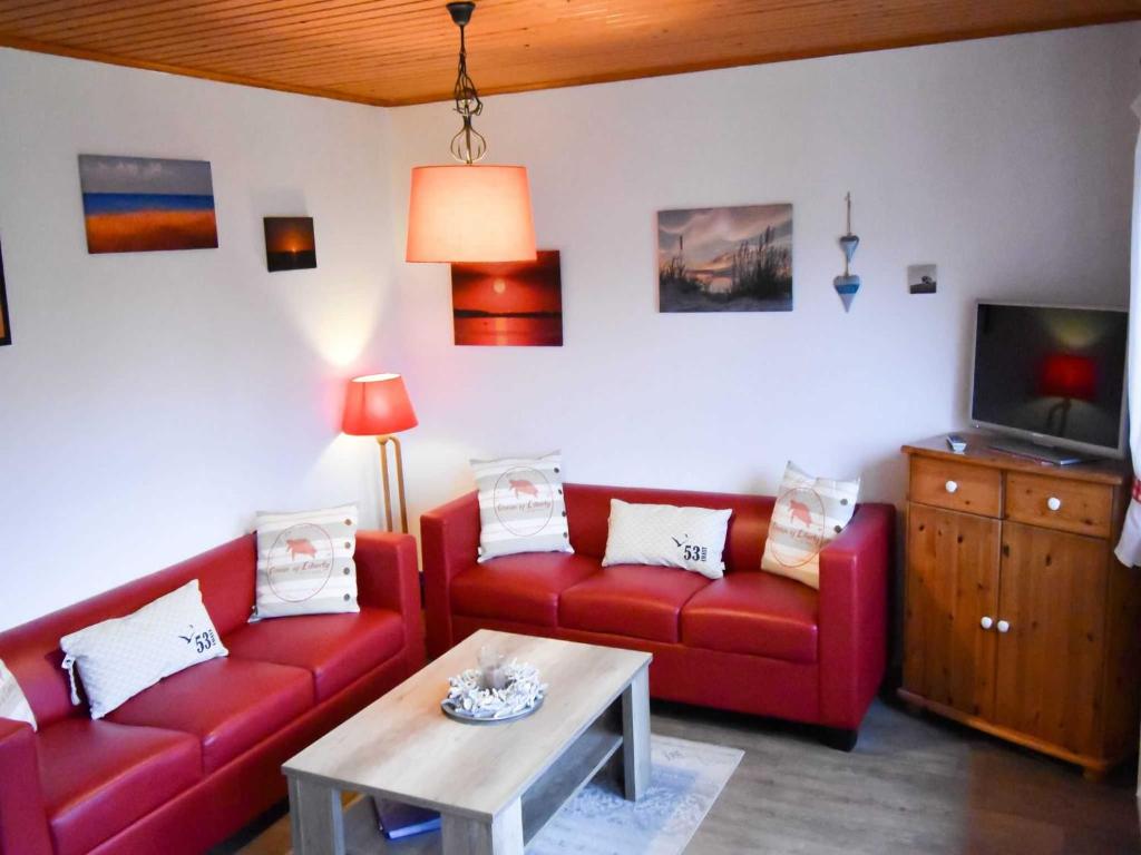 a living room with two red couches and a tv at Ferienhaus Deerberg in Hasselberg