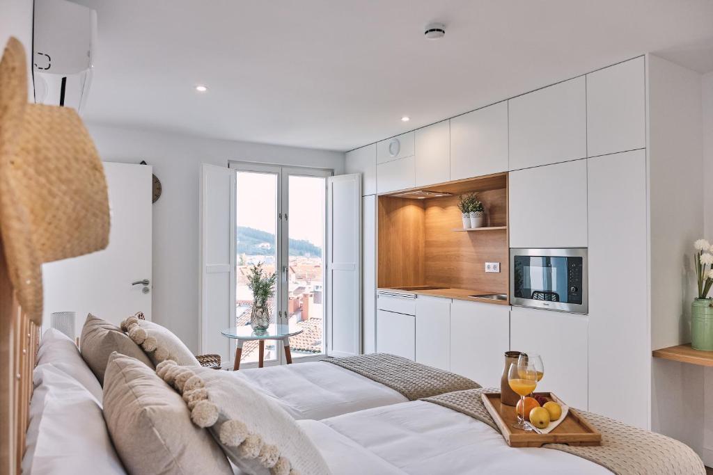 a white living room with a couch and a kitchen at ALDARA SUITES in Santiago de Compostela