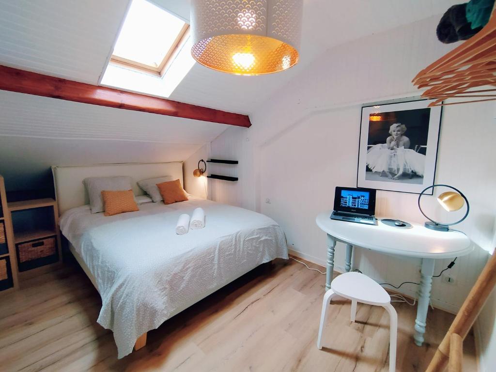 a bedroom with a bed and a desk with a laptop at Le Chalet d&#39;Amou in Bayonne