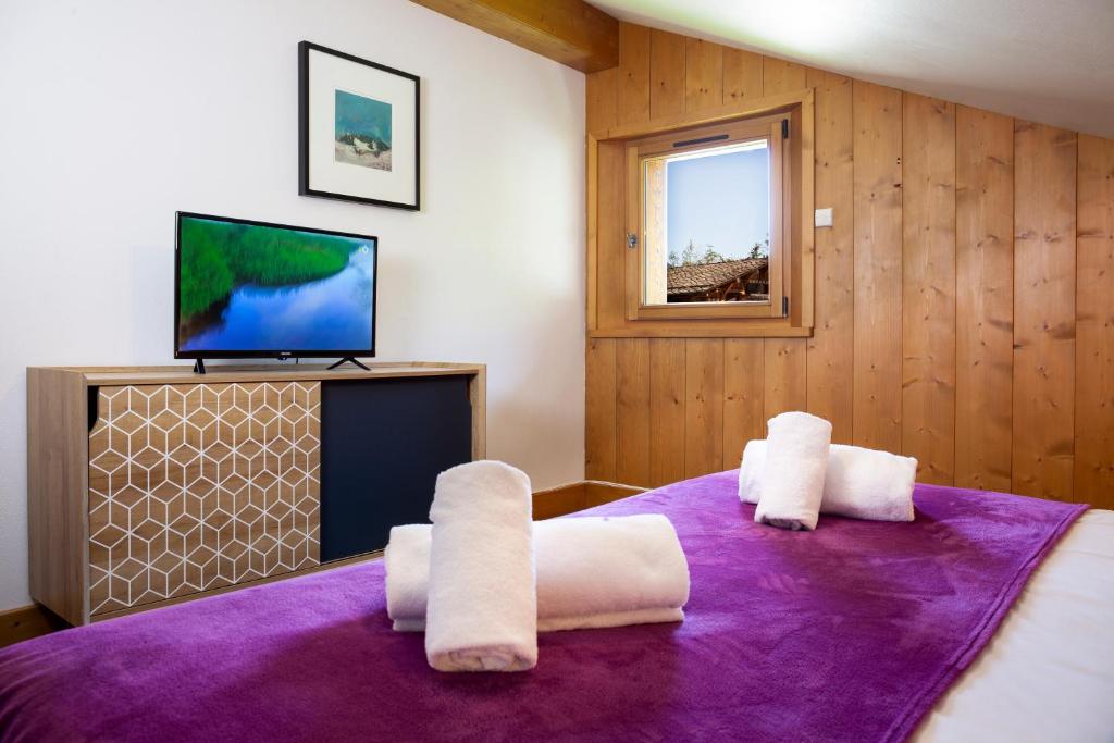 um quarto com uma cama roxa e toalhas brancas em Appartement Le Caboen Les Planards em Chamonix-Mont-Blanc