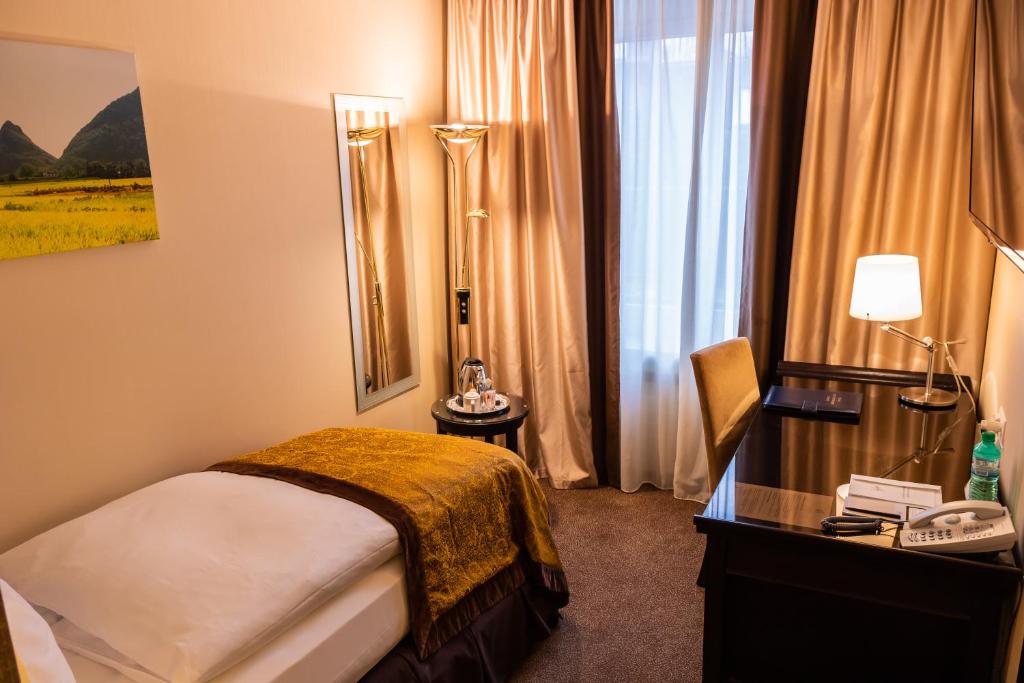 a hotel room with a bed and a desk and a window at Hotel St.Gotthard in Zürich