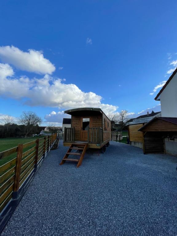 a small cabin with a fence and a house at Chez Célia, Roulotte en Champagne in Fleury-la-Rivière