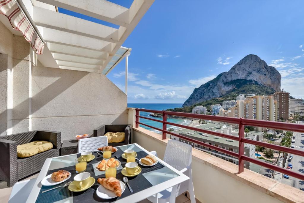 Un balcón con una mesa con comida y vistas al océano. en Apartamentos Zafiro Atico (3-12º-C), en Calpe