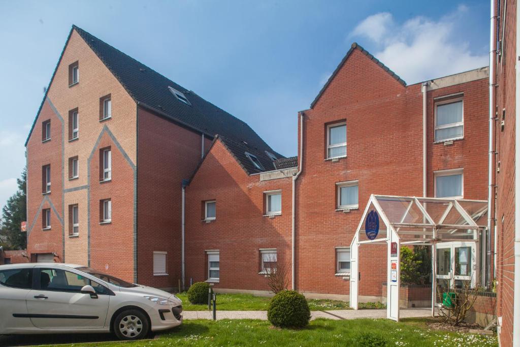 a brick building with a car parked in front of it at Hôtel Morphée Lille Villeneuve d'Ascq in Villeneuve d'Ascq