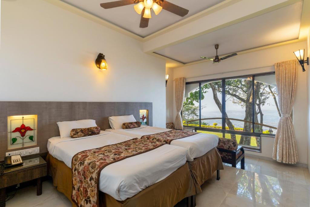 a bedroom with two beds and a large window at Valley View Grand Resort, Panhala - Premium Resort Hotel in Panhala in Panhāla