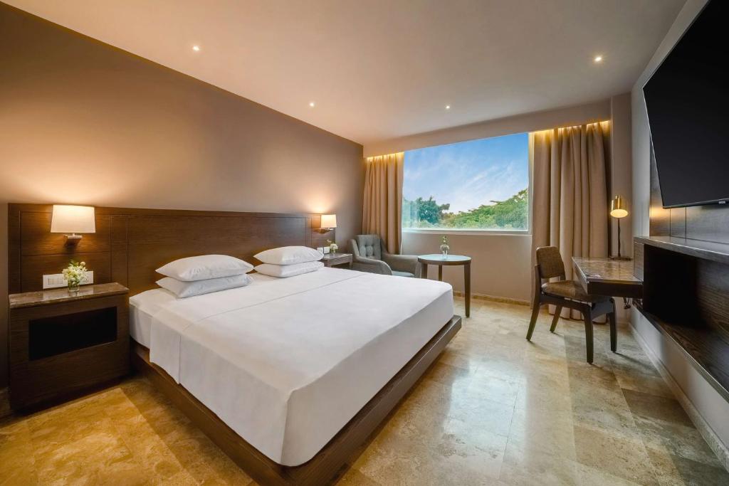 ein Schlafzimmer mit einem großen weißen Bett und einem Schreibtisch in der Unterkunft Hyatt Regency Villahermosa in Villahermosa