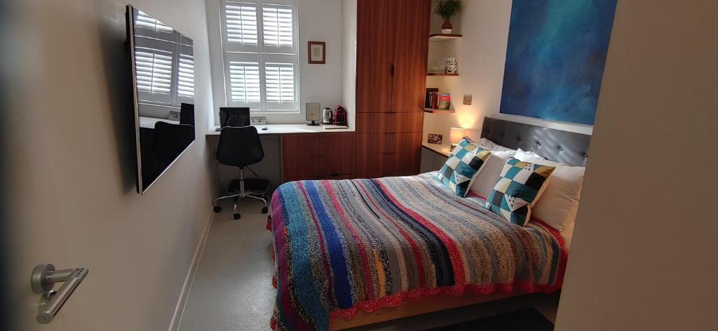Comfortable Room With Ensuite في لندن: غرفة نوم مع سرير وبطانية ملونة