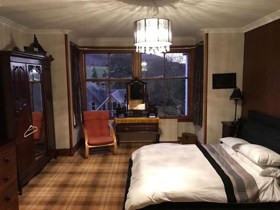 a bedroom with a bed and a desk and a window at The Brunstane Lodge in Strathpeffer