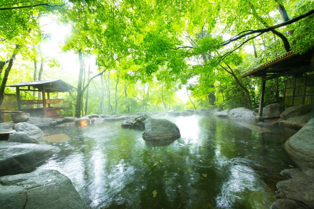 una corriente de agua con rocas y árboles en Nihon-no-Ashitaba en Yufuin