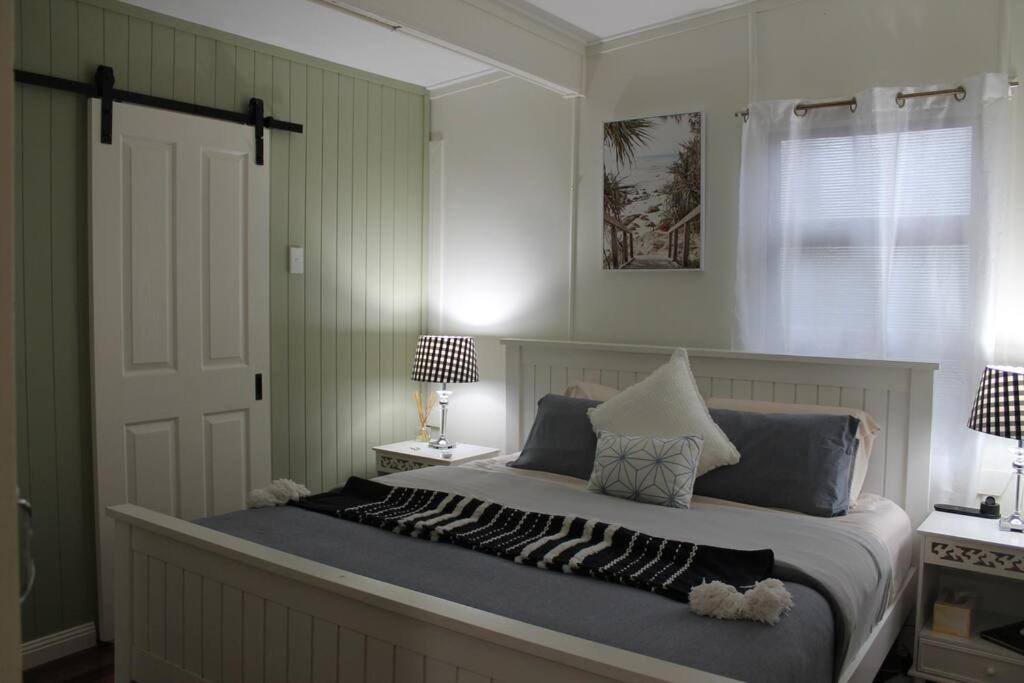 a bedroom with a bed with two lamps and a door at Little Ray on Sunshine. Hamptons style beachhouse in Woorim