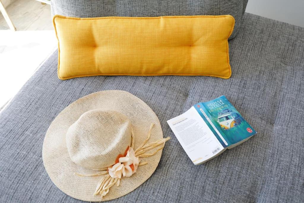 a straw hat sitting on a couch with a book and a pillow at ELEGANCE YourHostHelper in Le Cannet