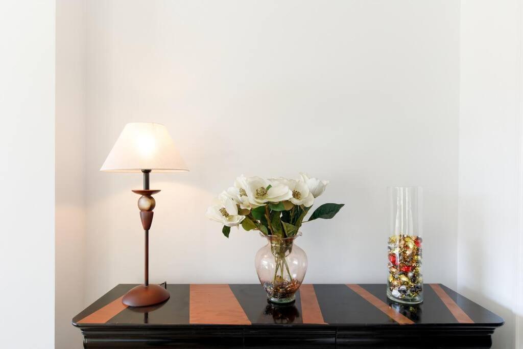 a table with a lamp and a vase with white flowers at ELEGANCE YourHostHelper in Le Cannet