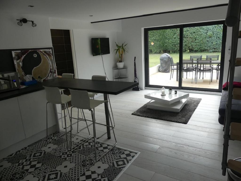 sala de estar con mesa y sillas y patio en Appartement 30 m2 neuf + terrasse, en Brindas