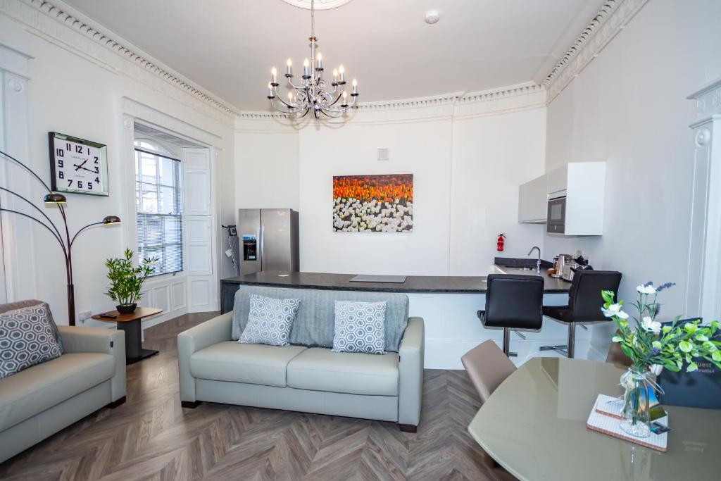 a living room with a couch and a kitchen at The Kensington Suite in Plymouth