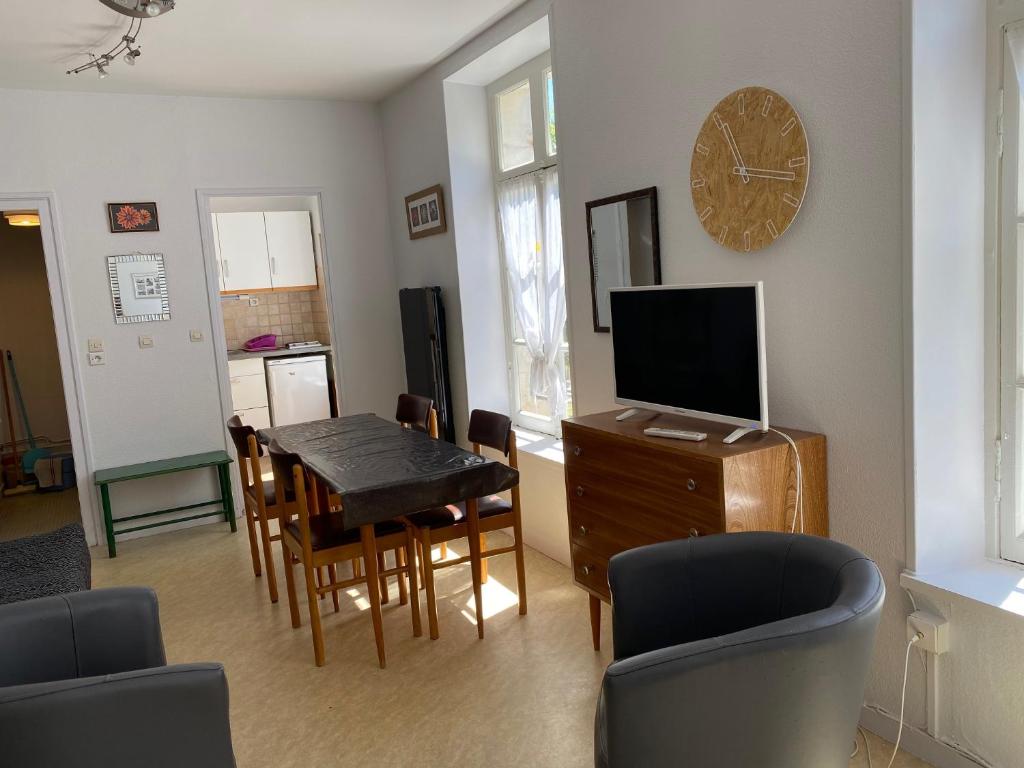 a living room with a dining room table and a television at Logis B21 in Rochefort