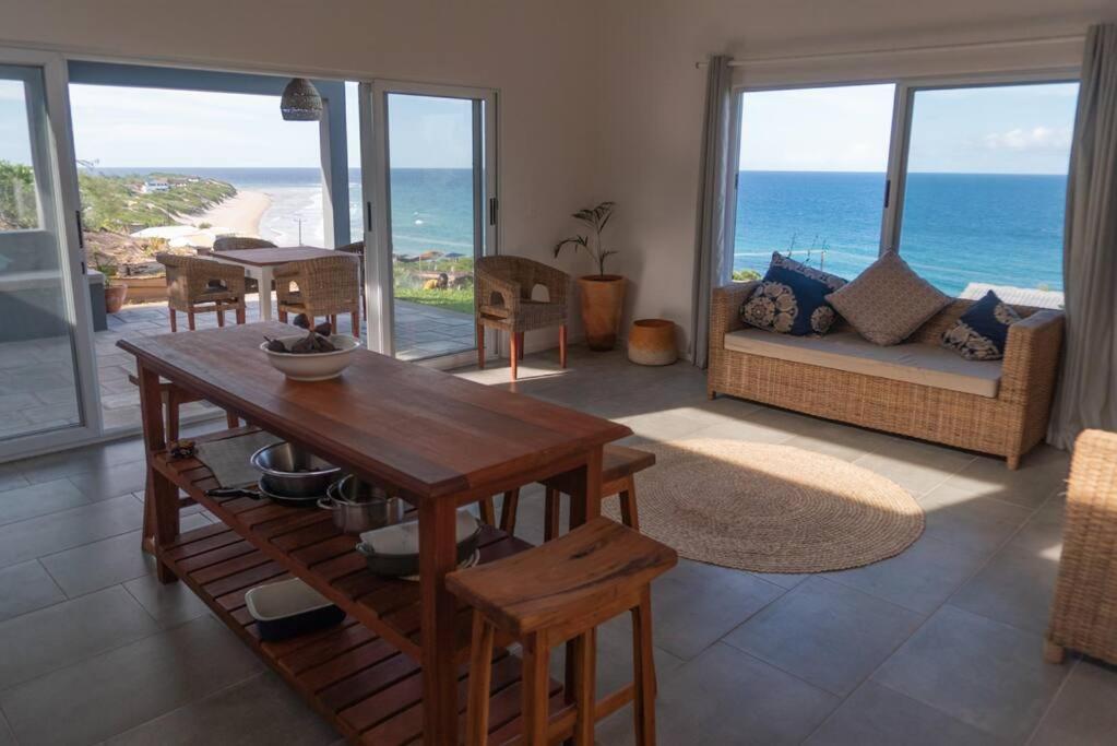 a living room with a table and views of the ocean at Coral Tree Surf Cottage - Tofinho, Tofo in Praia do Tofo