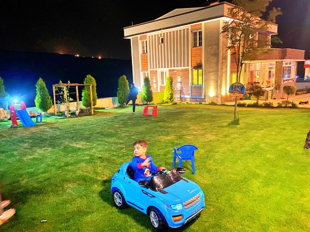 a young boy riding a toy car in a yard at Öztürk Farm House in Samsun
