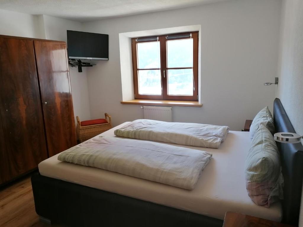 two beds in a room with a window and a tv at Ferienwohnung Knabl in Fliess