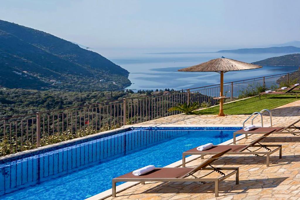 a swimming pool with two chairs and an umbrella at Athina Villas in Mikros Gialos