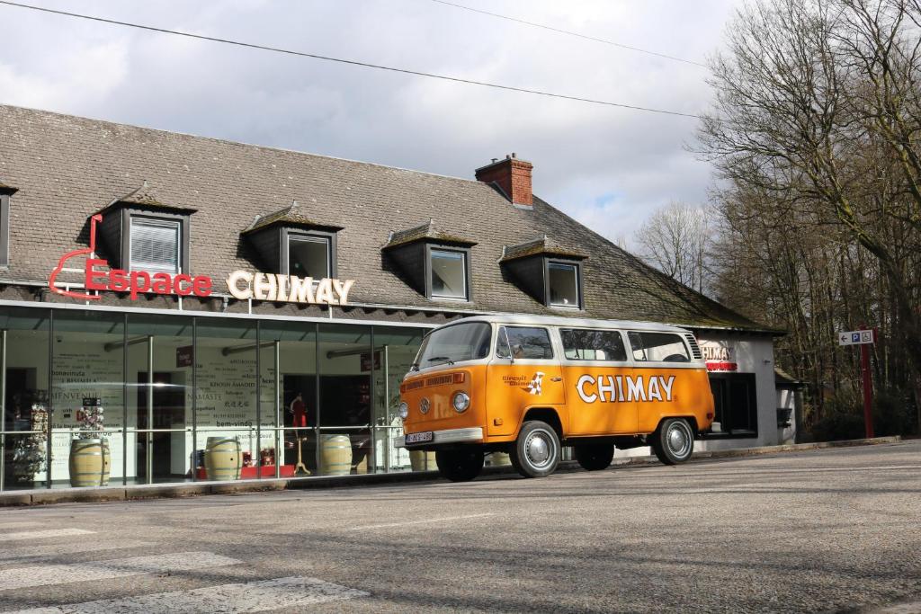 een oranje busje geparkeerd voor een gebouw bij Auberge de Poteaupré in Bourlers