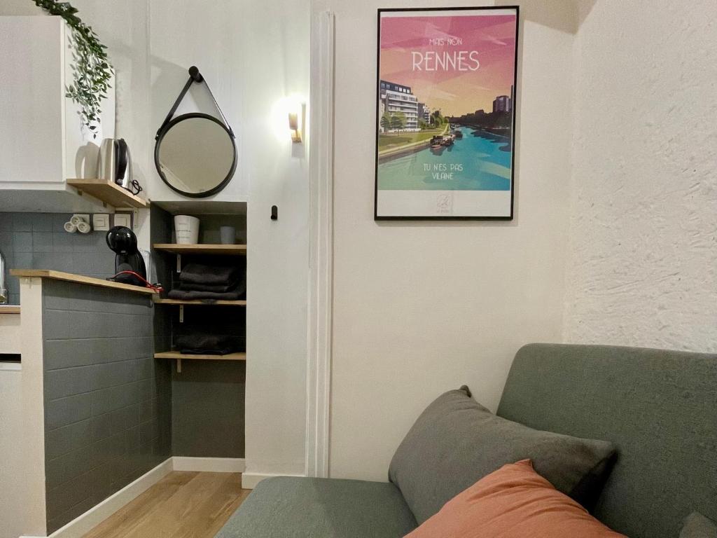 a living room with a couch and a poster on the wall at Le Cosy, charmant studio centre ville in Rennes