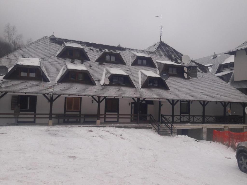 une grande maison avec de la neige sur le toit dans l'établissement Apartman Lily, à Brzeće