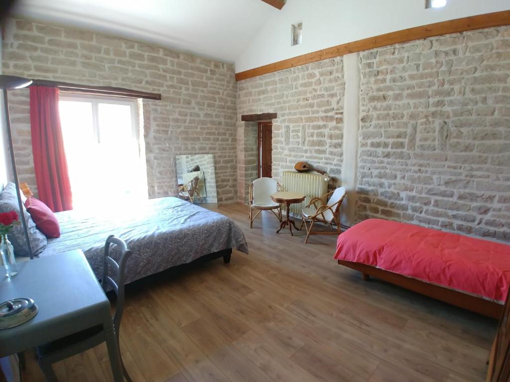 a bedroom with a brick wall and a bed and a window at 2 chambres privées au calme à la Maison des Bambous in Dijon