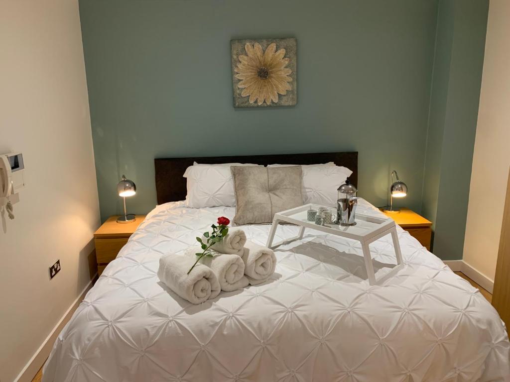a bedroom with a white bed with towels and a table at Modern, City Centre, Studio Apartment with FREE WIFI, GYM ACCESS, NETFLIX - West One in Sheffield