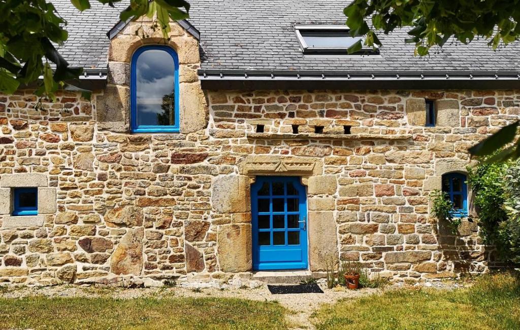 a stone building with a blue door and windows at Gîte de l&#39;Hirondelle bleue in Brech
