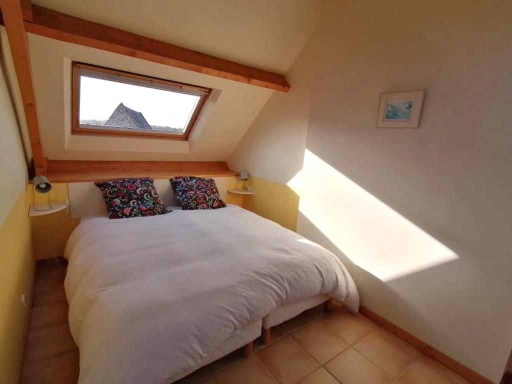 a bedroom with a bed in a attic with a window at Gîte de l&#39;Hirondelle bleue in Brech