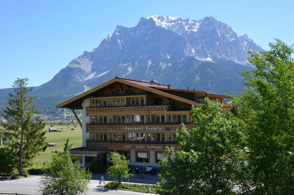 un gran edificio con una montaña en el fondo en Sporthotel Zugspitze en Lermoos