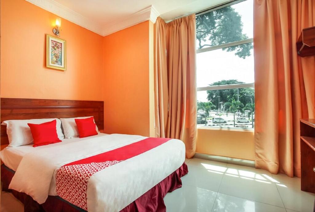 a bedroom with orange walls and a bed with red pillows at My Town Hotel in Ipoh