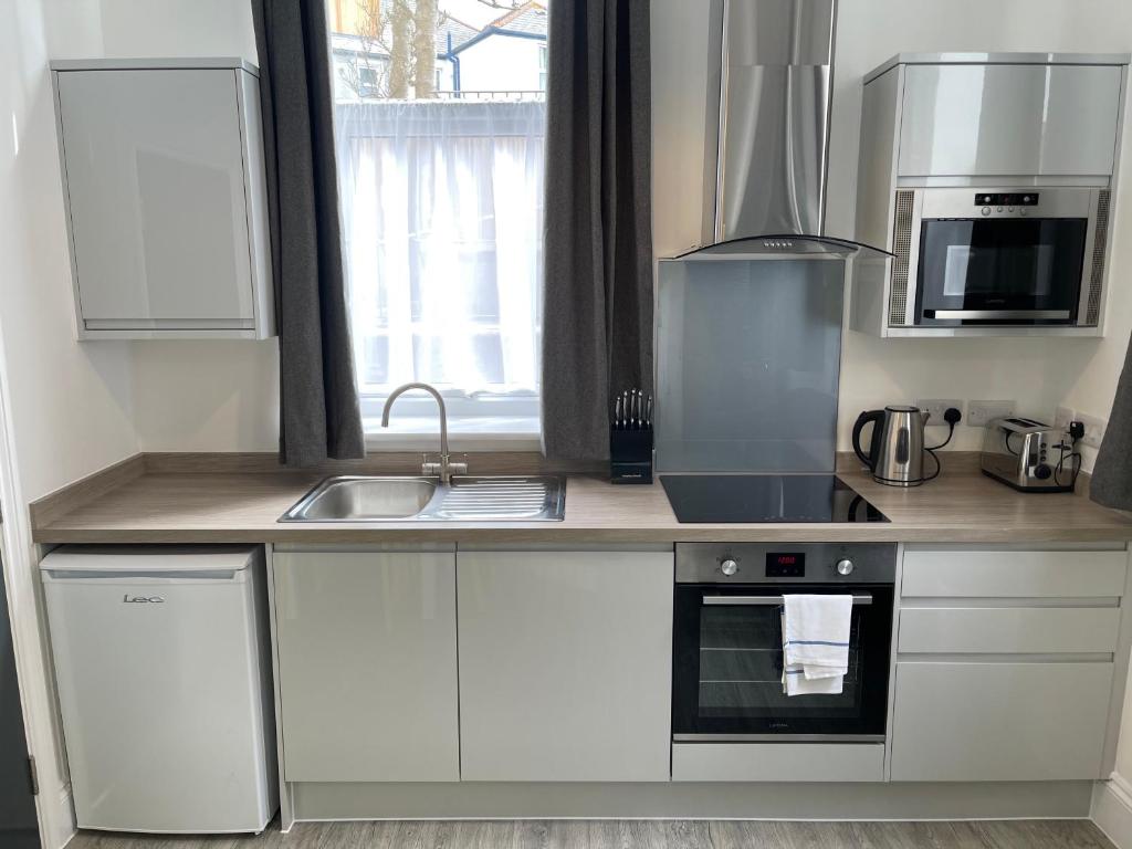 a kitchen with white cabinets and a sink at Marylebone by Pureserviced in Plymouth