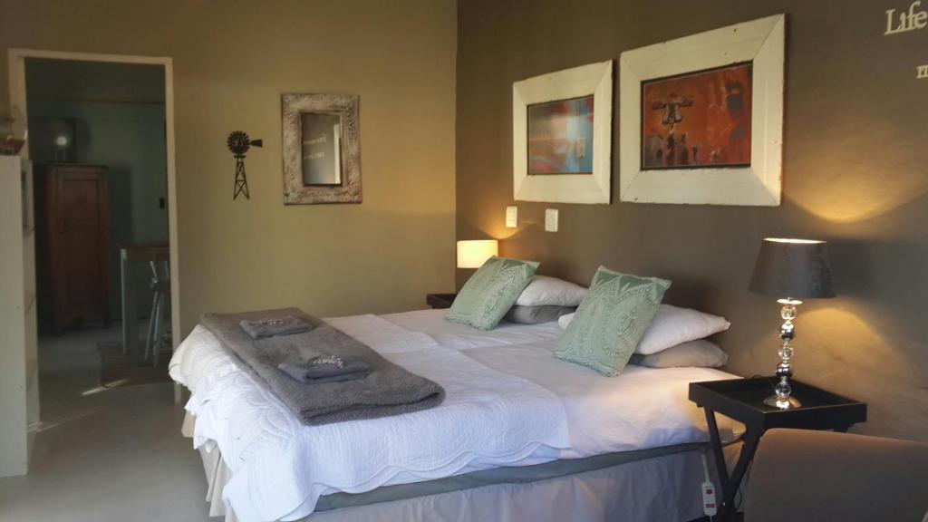 a bedroom with a large white bed with green pillows at Daisy Tree Cottage in Oudtshoorn