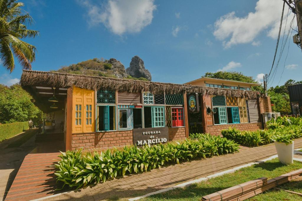 a small building with a mountain in the background at Ecocharme Pousada do Marcilio in Fernando de Noronha