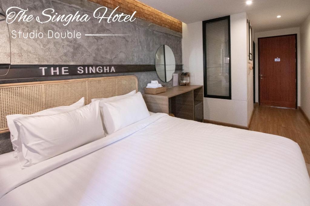 Schlafzimmer mit einem weißen Bett und einem Spiegel in der Unterkunft The Singha Hotel - Korat in Nakhon Ratchasima