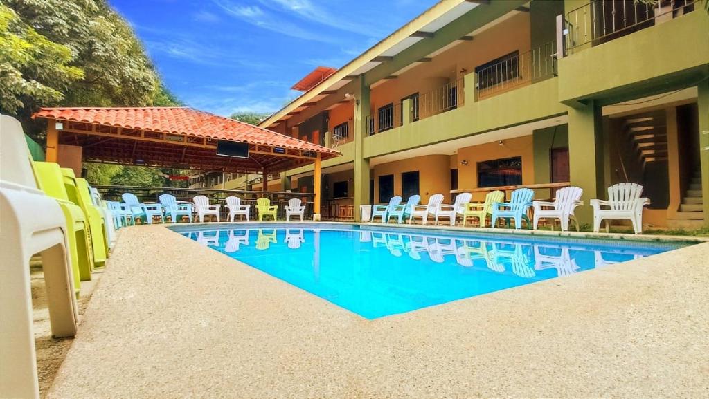 a swimming pool in front of a building with chairs at Coco Beach Condos in Guanacaste
