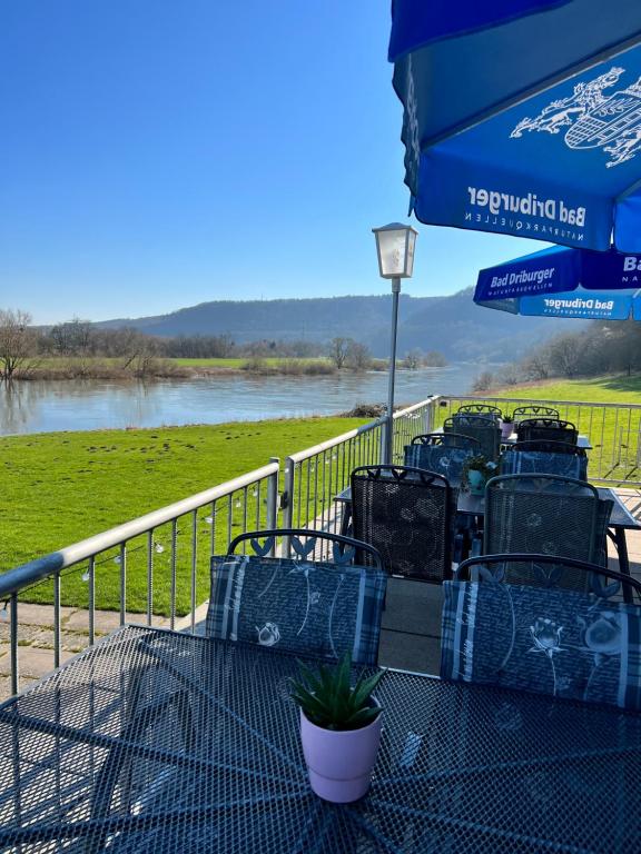 - une table avec des chaises et un parasol à côté d'une rivière dans l'établissement Camping am Bootshaus, à Beverungen